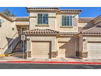 Inviting condo building featuring tan siding, multi-car garages, and stairs to upper units at 4630 Basilicata Ln # 203, North Las Vegas, NV 89084