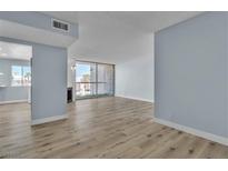 Bright living room featuring wood flooring, modern light-blue paint, a fireplace, and sliding glass doors to the balcony at 725 N Royal Crest Cir # 237, Las Vegas, NV 89169