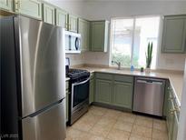 Well-lit kitchen featuring stainless steel appliances and light green cabinetry at 9236 Canalino Dr, Las Vegas, NV 89134