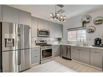 Modern kitchen featuring stainless steel appliances, gray cabinets, and decorative lighting at 10270 Gilmore Canyon Ct # 202, Las Vegas, NV 89129