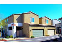 Two-story tan home with multiple garage doors and a street corner location at 12800 Oceano Dunes Ct, Henderson, NV 89044