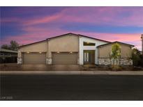Contemporary home featuring a three-car garage and modern design with stone accents and desert landscaping at sunset at 135 Barnett Crest Ct, Henderson, NV 89015