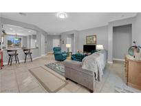 Open-concept living room with neutral tones, tile floors, and modern furnishings at 2709 Rue Montpellier Ave, Henderson, NV 89044