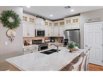Bright kitchen with white cabinets, stainless steel appliances and large center island with marble countertop at 3185 Mura Del Prato Ave, Henderson, NV 89044