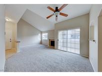 Bright living room with vaulted ceilings, neutral carpet, fireplace and sliding door to patio at 331 Seine Way # 331, Henderson, NV 89014