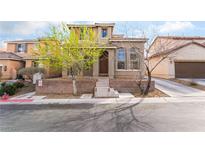 Two-story tan home featuring a brick front wall and a well-maintained lawn with mature trees at 9119 Brilliant Prairie Ct, Las Vegas, NV 89149