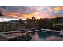 Inviting pool with water features, set against a backdrop of a vibrant sunset and palm trees at 11241 Golden Chestnut Pl, Las Vegas, NV 89135