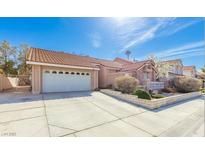 Charming single-story home featuring a two-car garage, well-maintained landscaping, and a tile roof on a sunny day at 3040 Ocean Port Dr, Las Vegas, NV 89117