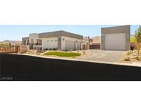 Modern home with a circular driveway, multiple garages, and desert landscaping at 5719 Christian Creek Ct, Las Vegas, NV 89149