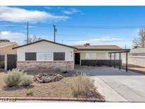 Charming single-story home featuring a brick facade and attached carport under a sunny blue sky at 613 Kings Pl, Boulder City, NV 89005