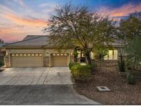 Charming single-story home featuring a three-car garage, stone accents, and mature landscaping at sunset at 3806 Internet Ave, North Las Vegas, NV 89031