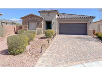 Inviting single-story home with a stone facade, desert landscaping and a paver driveway leading to a two-car garage at 5555 E San Pietro Dr, Pahrump, NV 89061