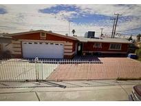 Cozy one-story home featuring a convenient garage and a fenced brick driveway, perfect for secure parking at 609 S Mallard St, Las Vegas, NV 89107
