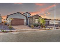 Charming single-story home featuring desert landscaping, brick driveway, and a stone-accented facade at sunset at 827 Klamath Springs St, Henderson, NV 89011