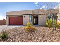 Contemporary single-story home featuring a red garage door and low maintenance desert landscaping at 8795 Stella Nova St, Las Vegas, NV 89139