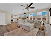 Bright and spacious living room with plush sectional seating, modern ceiling fan and open floorplan to the kitchen at 10973 Sardinia Sands Dr, Las Vegas, NV 89141
