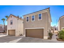 Beige two-story home featuring brown trim, a tile roof and an attached garage, all under a clear blue sky at 1425 Bow Creek Ct, Las Vegas, NV 89128