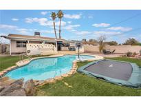 Backyard pool with lush grass, palm trees, and a trampoline. Perfect for summer fun at 212 N Torrey Pines Dr, Las Vegas, NV 89107