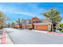 Charming townhomes with attached garages and well-maintained landscaping under a clear blue sky at 821 Glacier Peak Ln # 203, Las Vegas, NV 89144