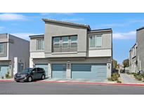 Modern two-story home featuring gray stucco, a balcony, and light blue garage doors against a blue sky at 4932 Chidlaw Ave # 2, Las Vegas, NV 89115