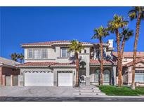 Stunning two-story home with a three-car garage and lush tropical landscaping including mature palm trees at 8864 La Manga Ave, Las Vegas, NV 89147