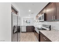 Beautiful kitchen featuring stainless steel appliances, granite countertops, and dark wood cabinetry at 12367 Indigo Montage Rd # 3, Las Vegas, NV 89183