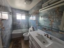Modern bathroom featuring marbled walls, a tub-shower, and a white vanity with undermount sink at 4342 E Russell Rd, Las Vegas, NV 89120