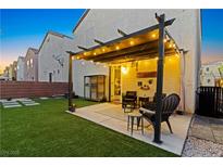 Inviting backyard patio features a pergola with string lights and a well-maintained lawn at 6645 Churnet Valley Ave, Las Vegas, NV 89139
