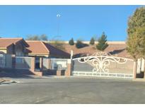 View of ornate white entrance gate to private, desert-landscaped community with a tiled roof house visible at 1163 Spanish Armada Rd, Las Vegas, NV 89123