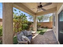 Covered patio featuring brick flooring, outdoor seating, fan, and views of the backyard landscaping at 168 Springhouse St, Las Vegas, NV 89148