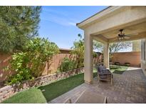 Relaxing covered patio area features brick pavers, artificial grass, and comfortable seating for enjoying the outdoors at 168 Springhouse St, Las Vegas, NV 89148