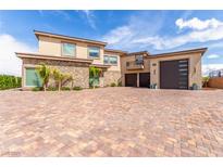 Stunning exterior with brick driveway, stone accents, a three car garage, and a private balcony at 386 Cactus River Ct, Henderson, NV 89052