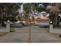 Expansive home featuring a circular driveway, mature trees, and three-car garage at 6998 Alamitos Cir, Las Vegas, NV 89120