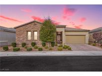 Charming single-story home with a stone facade, manicured landscaping, and a two-car garage at sunset at 2450 Amatrice St, Henderson, NV 89044