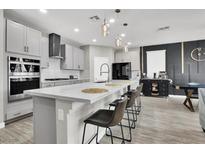 Modern kitchen features a large island with bar seating, pendant lights, and stainless steel appliances at 4588 Swimming Minnow Ave, Las Vegas, NV 89141