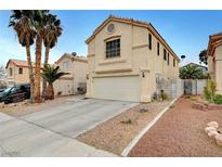 Beige two-story home with a two-car garage, desert landscaping, and towering palm trees in the front yard at 9143 Bucksprings Dr, Las Vegas, NV 89129