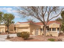 Single-story home with a tan exterior, tile roof, front yard landscaping, and a two-car garage at 2553 Showcase Dr, Las Vegas, NV 89134