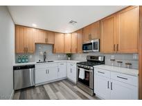 Updated kitchen with stainless steel appliances, wood cabinets, quartz counters, and gray subway tile backsplash at 405 Frederick Ave, Las Vegas, NV 89106