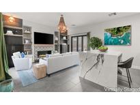 Bright living room with fireplace, decorative shelving, stylish furnishings and a marble waterfall island at 2876 Strathallan Ave, Henderson, NV 89044