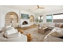 Bright living room featuring a fireplace, modern ceiling fan, and large sliding doors to the backyard at 10420 Luella Ct, Las Vegas, NV 89143