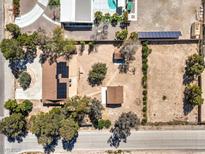 Aerial view of a property featuring a house with solar panels, expansive land, and a neighboring pool at 10615 Rancho Destino Rd, Las Vegas, NV 89183
