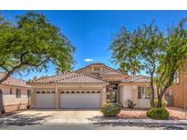Charming home featuring a three-car garage, desert landscaping, and a tile roof in a lush setting with mature trees at 1363 Rolling Sunset St, Henderson, NV 89052