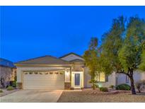 Charming single-story home featuring a two-car garage and beautifully landscaped front yard at dusk at 2583 Moonlight Valley Ave, Henderson, NV 89044