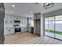 Bright kitchen featuring gray cabinets, stainless appliances, and a sliding glass door leading to the patio at 341 Greenbriar Townhouse Way, Las Vegas, NV 89121