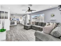 Open concept living room featuring a comfortable gray couch, modern ceiling fan, and wood-look floors at 5582 Tunis Ave, Las Vegas, NV 89122