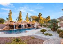 Resort-style pool featuring a rock waterfall, slide, lush landscaping and patio at 6004 Chessington Ave, Las Vegas, NV 89131