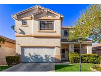 Two-story home showcasing a garage, trimmed lawn, complementary bushes, and a beautiful blue sky at 9020 Loggers Mill Ave, Las Vegas, NV 89143