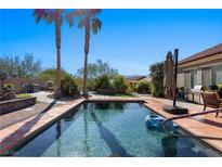 Beautiful backyard pool and patio featuring tall palm trees and desert landscaping at 950 Overland Trl, Mesquite, NV 89034