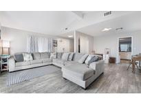 Bright living room with large sectional sofa and wood-look tile flooring at 6320 Vicuna Dr, Las Vegas, NV 89146