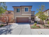 Tan two-story home with stone accents, a brown garage door, manicured landscaping, and a concrete driveway at 1427 Brushback Ave, Henderson, NV 89074